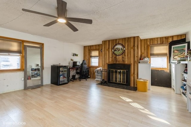 living room with light hardwood / wood-style floors, a textured ceiling, and ceiling fan