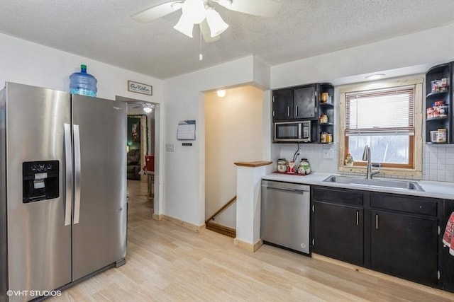 kitchen with light wood-type flooring, appliances with stainless steel finishes, backsplash, and sink