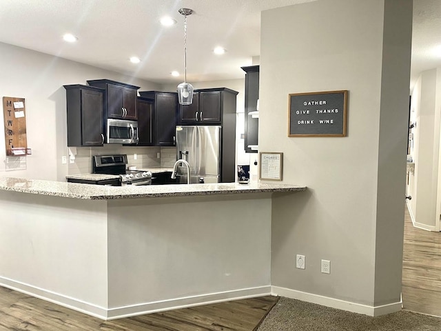 kitchen featuring backsplash, kitchen peninsula, dark hardwood / wood-style flooring, and stainless steel appliances