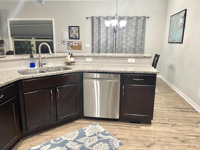 kitchen with light wood-type flooring, light stone counters, sink, decorative light fixtures, and dishwasher