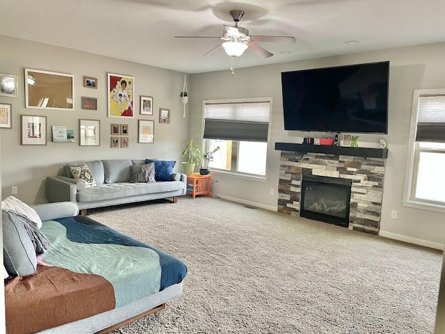 living room with carpet flooring, ceiling fan, a fireplace, and a wealth of natural light