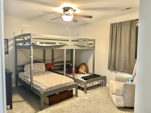 carpeted bedroom with ceiling fan and a textured ceiling