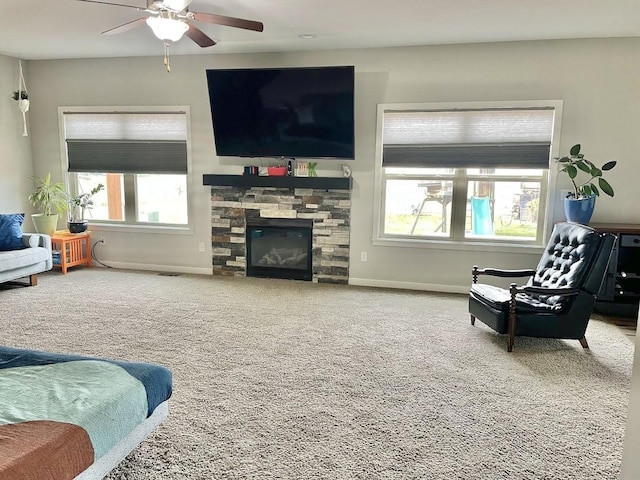 living room featuring ceiling fan, a fireplace, carpet, and a healthy amount of sunlight