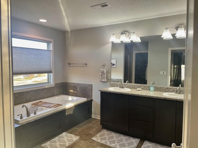 bathroom featuring vanity, a textured ceiling, tile patterned floors, and a bathing tub