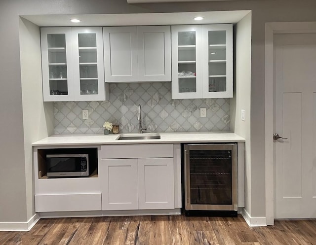 bar with dark hardwood / wood-style flooring, sink, beverage cooler, and tasteful backsplash