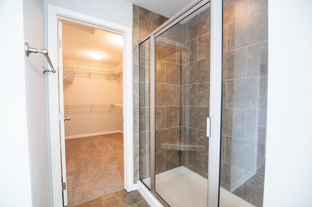 full bath with tile patterned flooring, a spacious closet, and a shower stall
