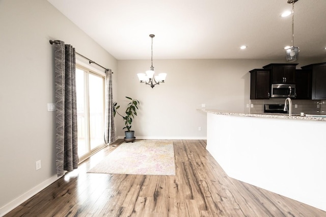 kitchen featuring backsplash, stainless steel microwave, light wood finished floors, a notable chandelier, and recessed lighting