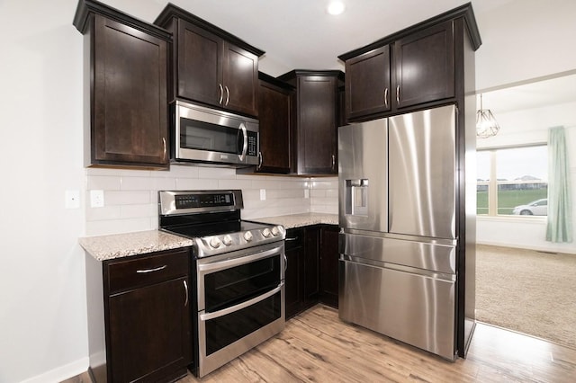 kitchen featuring stainless steel appliances, baseboards, decorative backsplash, and dark brown cabinets