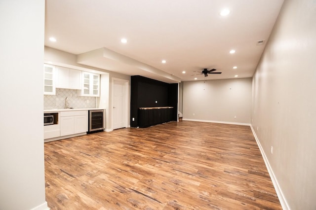 interior space featuring beverage cooler, recessed lighting, wet bar, and light wood-style floors