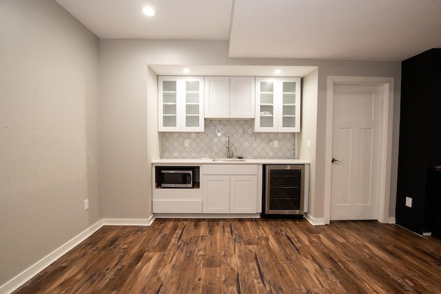 bar featuring tasteful backsplash, a sink, baseboards, indoor wet bar, and wine cooler