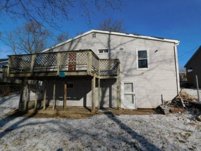 snow covered back of property with a deck