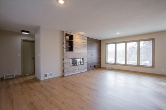 unfurnished living room with light hardwood / wood-style floors and a tiled fireplace