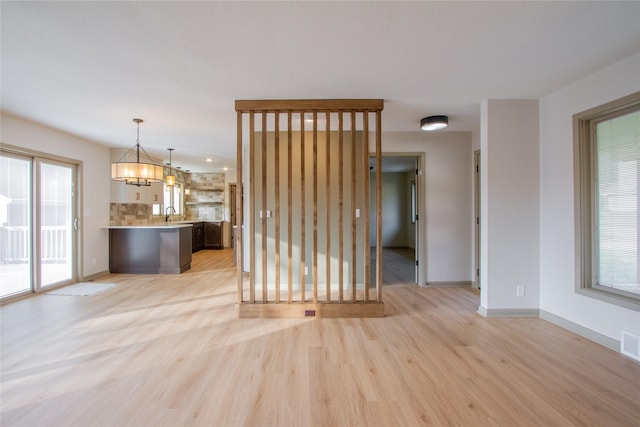 unfurnished living room with a notable chandelier, light hardwood / wood-style floors, and sink