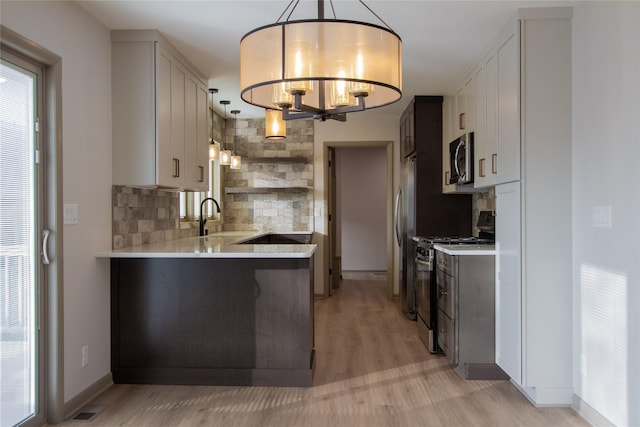 kitchen with decorative backsplash, stainless steel appliances, pendant lighting, white cabinets, and light hardwood / wood-style floors