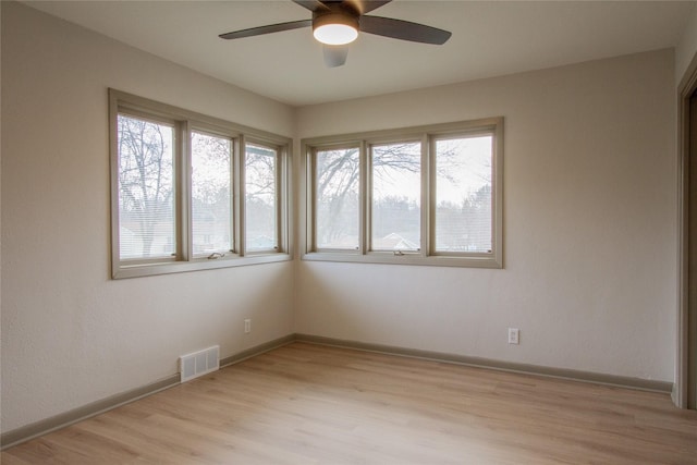 empty room with a wealth of natural light, light hardwood / wood-style flooring, and ceiling fan