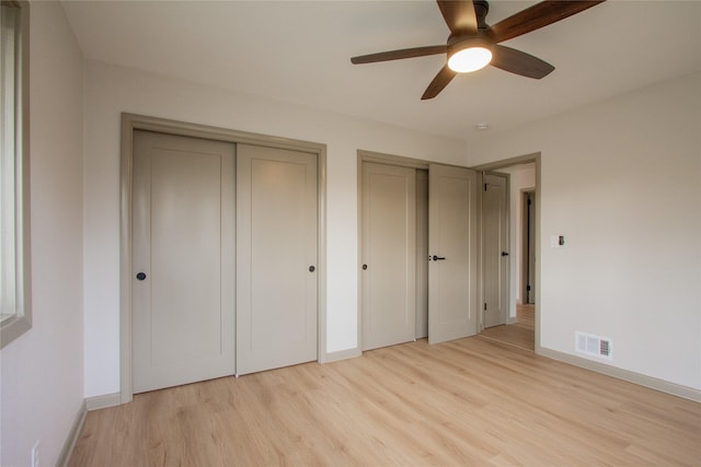 unfurnished bedroom featuring two closets, light hardwood / wood-style flooring, and ceiling fan