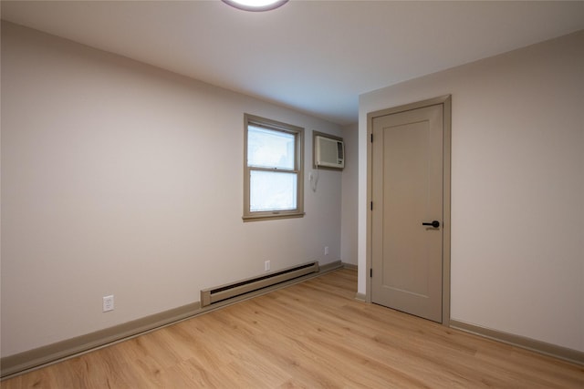 empty room featuring light hardwood / wood-style floors, a wall unit AC, and baseboard heating