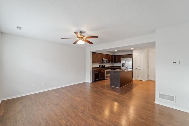 kitchen featuring a kitchen island with sink, stainless steel appliances, ceiling fan, dark hardwood / wood-style flooring, and dark brown cabinetry