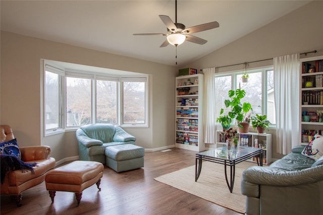 living area with lofted ceiling, ceiling fan, wood-type flooring, and a wealth of natural light