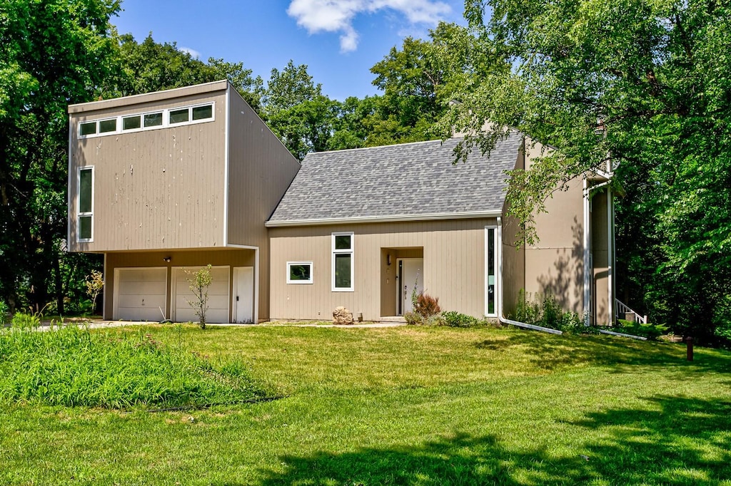 back of property featuring a lawn and a garage