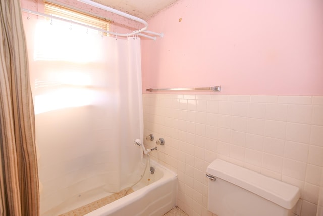 bathroom with toilet, tile walls, and shower / tub combo with curtain