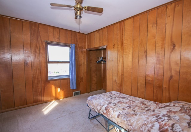 unfurnished bedroom with carpet flooring, ceiling fan, and wood walls