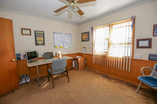 carpeted home office with ceiling fan and wooden walls