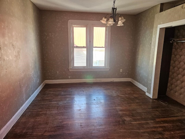 unfurnished room featuring dark hardwood / wood-style flooring and an inviting chandelier