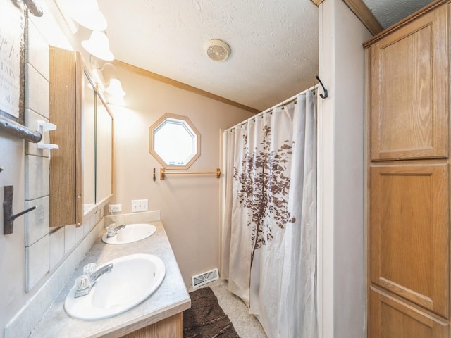 bathroom featuring a textured ceiling, vanity, crown molding, and walk in shower