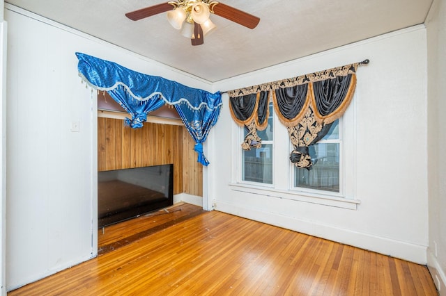 unfurnished living room featuring hardwood / wood-style floors, a textured ceiling, ceiling fan, and wooden walls