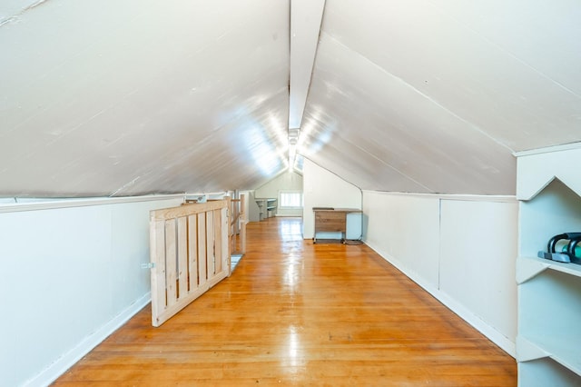 additional living space featuring light wood-type flooring and vaulted ceiling