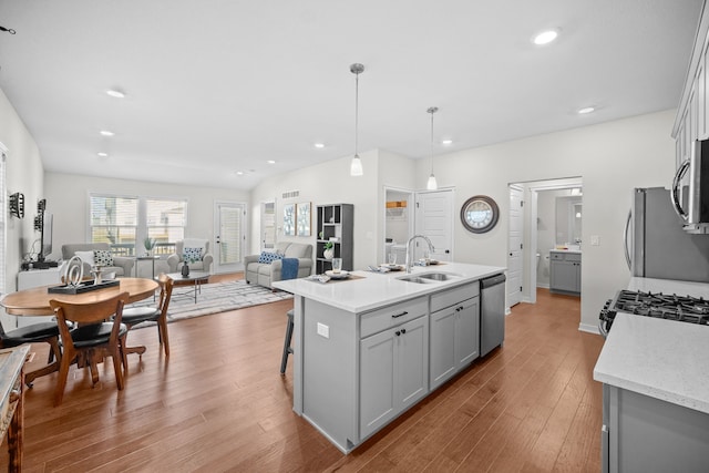 kitchen featuring gray cabinetry, sink, an island with sink, appliances with stainless steel finishes, and decorative light fixtures