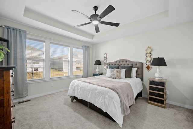 bedroom featuring a raised ceiling, ceiling fan, and carpet