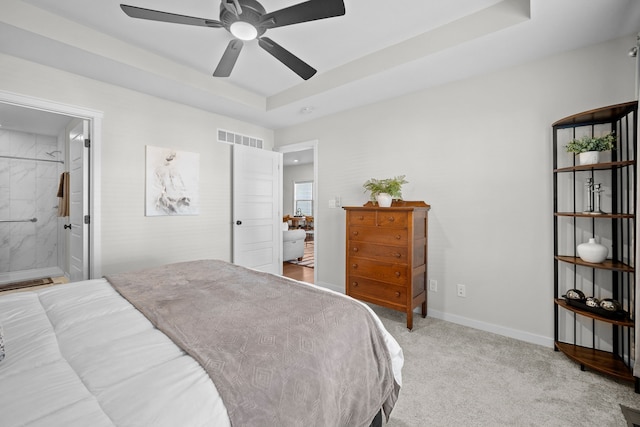 bedroom with ensuite bathroom, ceiling fan, light colored carpet, and a tray ceiling