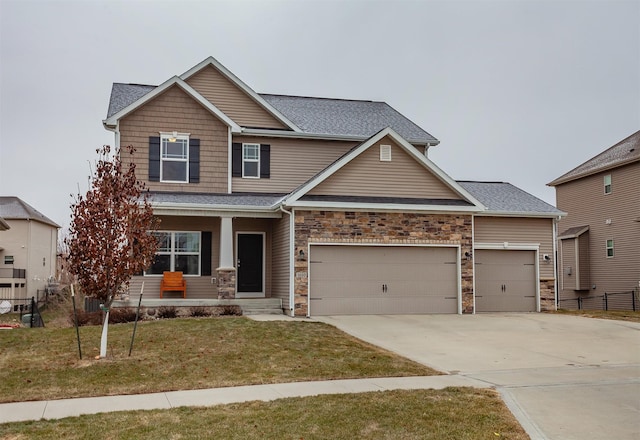 craftsman-style house with an attached garage, covered porch, concrete driveway, stone siding, and a front yard