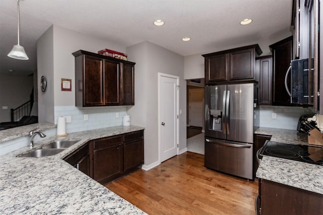 kitchen featuring dark brown cabinetry, stainless steel fridge, black microwave, and a sink