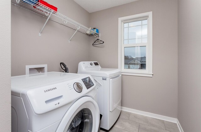 washroom with laundry area, light tile patterned floors, baseboards, and separate washer and dryer