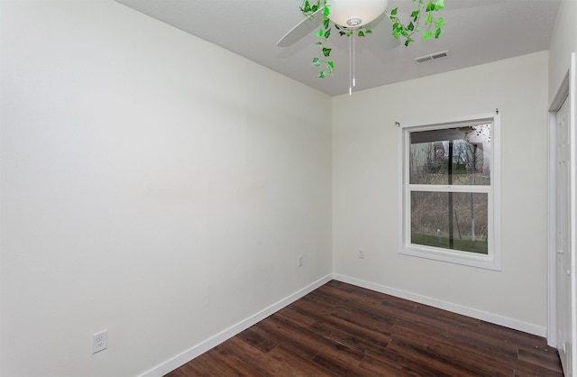 spare room with baseboards, visible vents, ceiling fan, and dark wood-style flooring