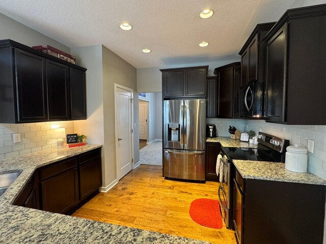 kitchen featuring light stone countertops, tasteful backsplash, stainless steel appliances, and light wood-style floors