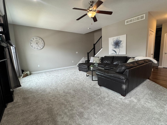 living room with carpet floors, a ceiling fan, visible vents, stairs, and baseboards