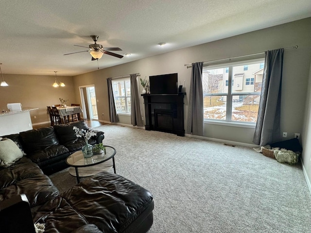 carpeted living area with a fireplace, baseboards, and a textured ceiling