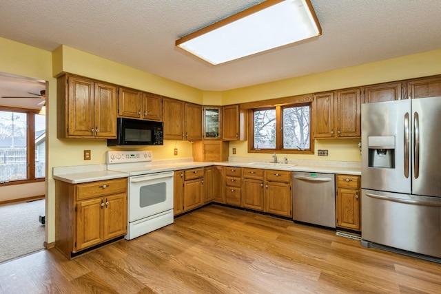 kitchen featuring sink, a textured ceiling, light wood-type flooring, ceiling fan, and stainless steel appliances