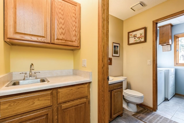 bathroom with vanity, washer and dryer, tile patterned floors, and toilet