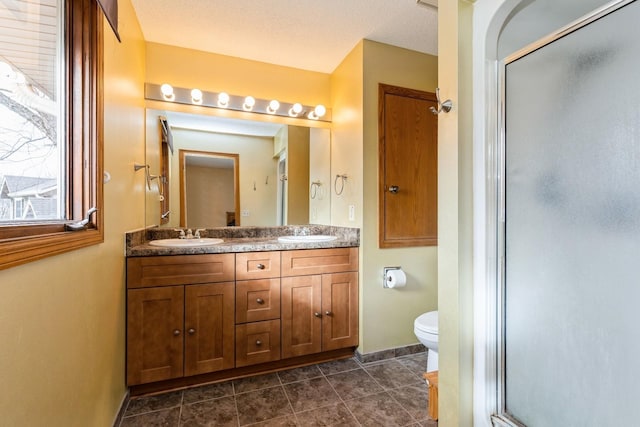 bathroom with vanity, toilet, a textured ceiling, and a shower with shower door