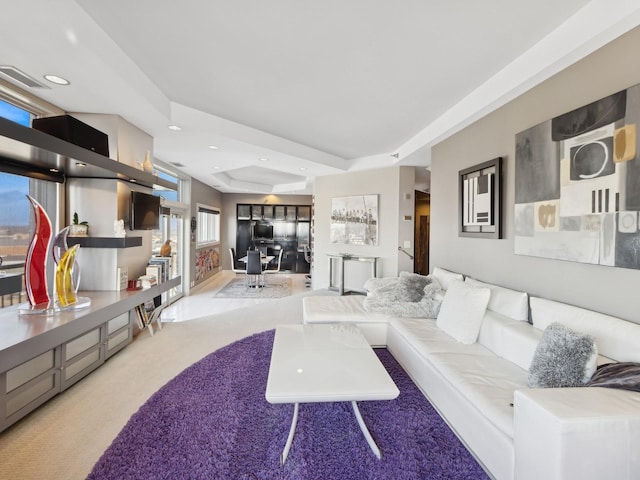 living room featuring light carpet and a tray ceiling