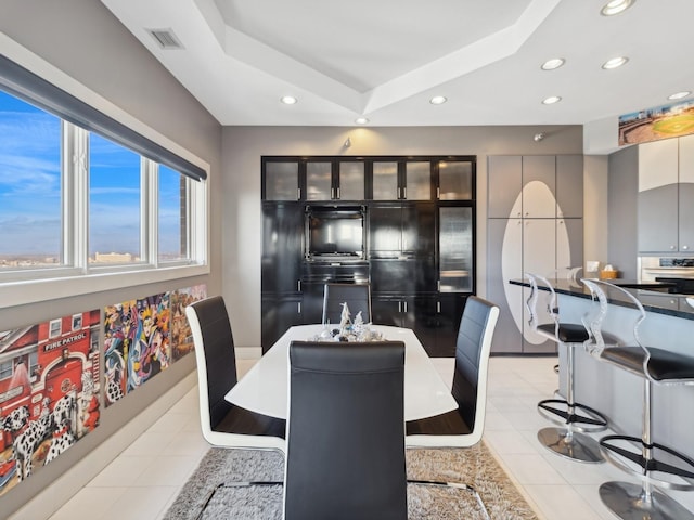 tiled dining room featuring a raised ceiling