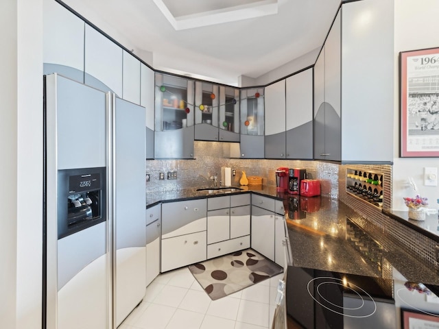 kitchen featuring gray cabinetry, backsplash, sink, light tile patterned floors, and refrigerator with ice dispenser