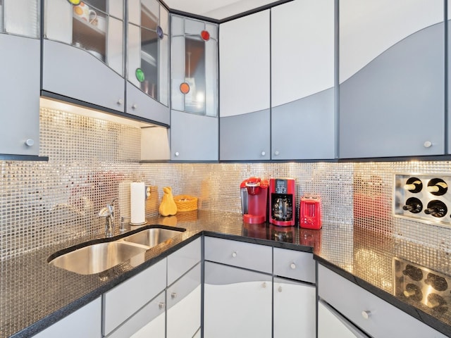 kitchen with tasteful backsplash, white cabinetry, and sink