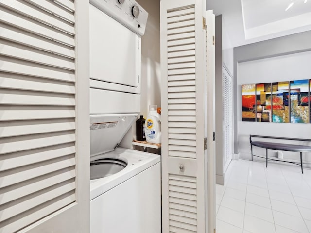 laundry area featuring light tile patterned floors and stacked washing maching and dryer