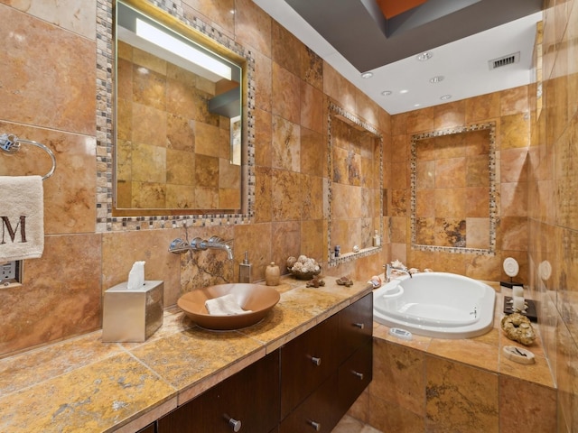 bathroom with tiled bath, vanity, and tile walls